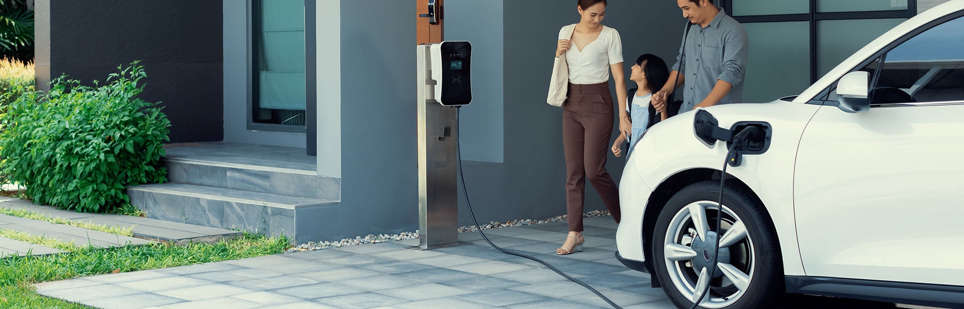 family walk in front of car being charge